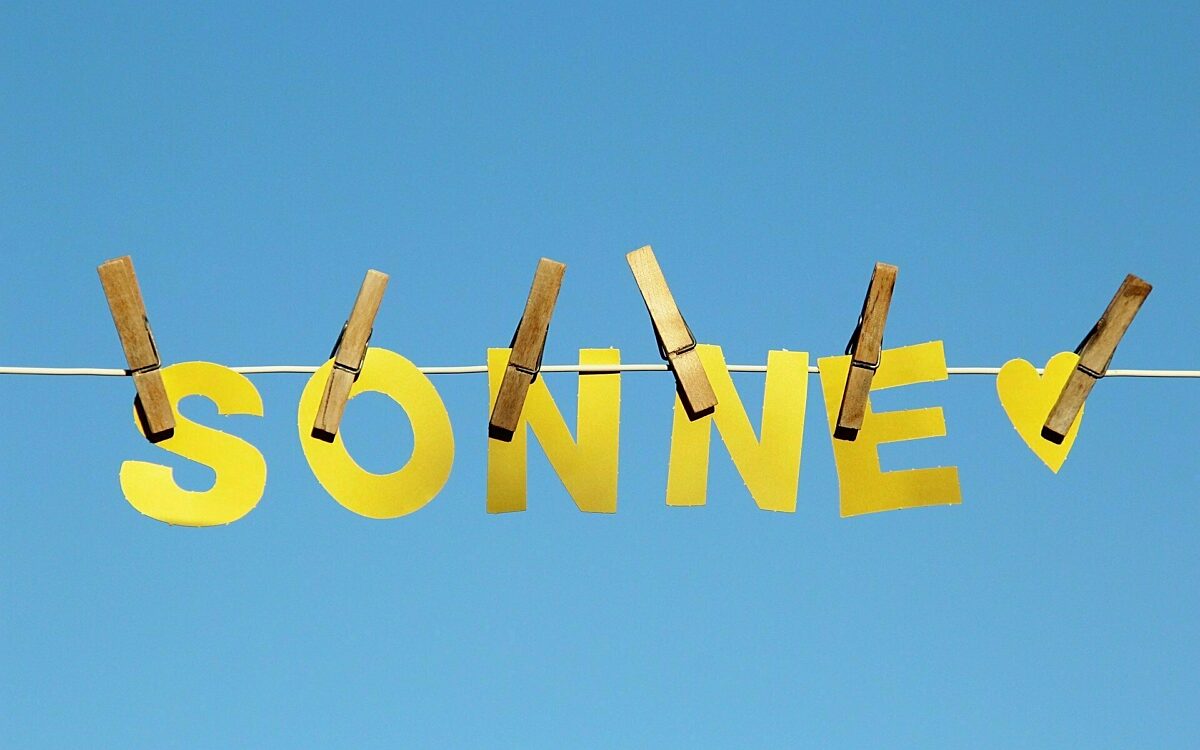 Das Wort Sonne in Buchstaben mit Wäscheklammern an Wäscheleine vor blauem Himmel Das Wort Sonne in Buchstaben mit Wäscheklammern an Wäscheleine vor blauem Himmel